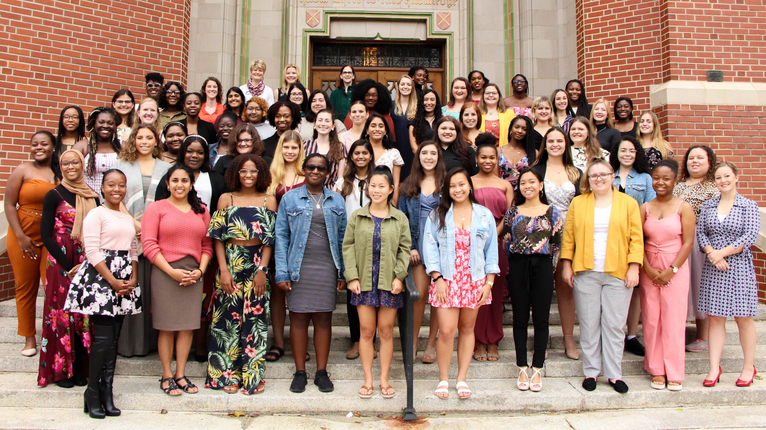 A large group of women standing outside on steps, smiling