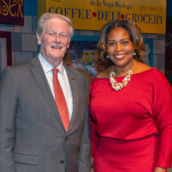 A photo of Felicia Brunson wearing a red dress, smiling, standing with a man wearing a gray suit