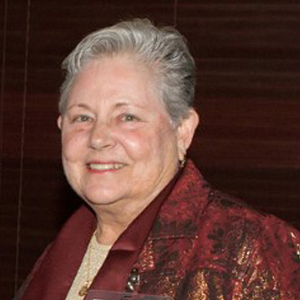 A headshot of Alicia Crew, smiling, wearing a burgundy jacket