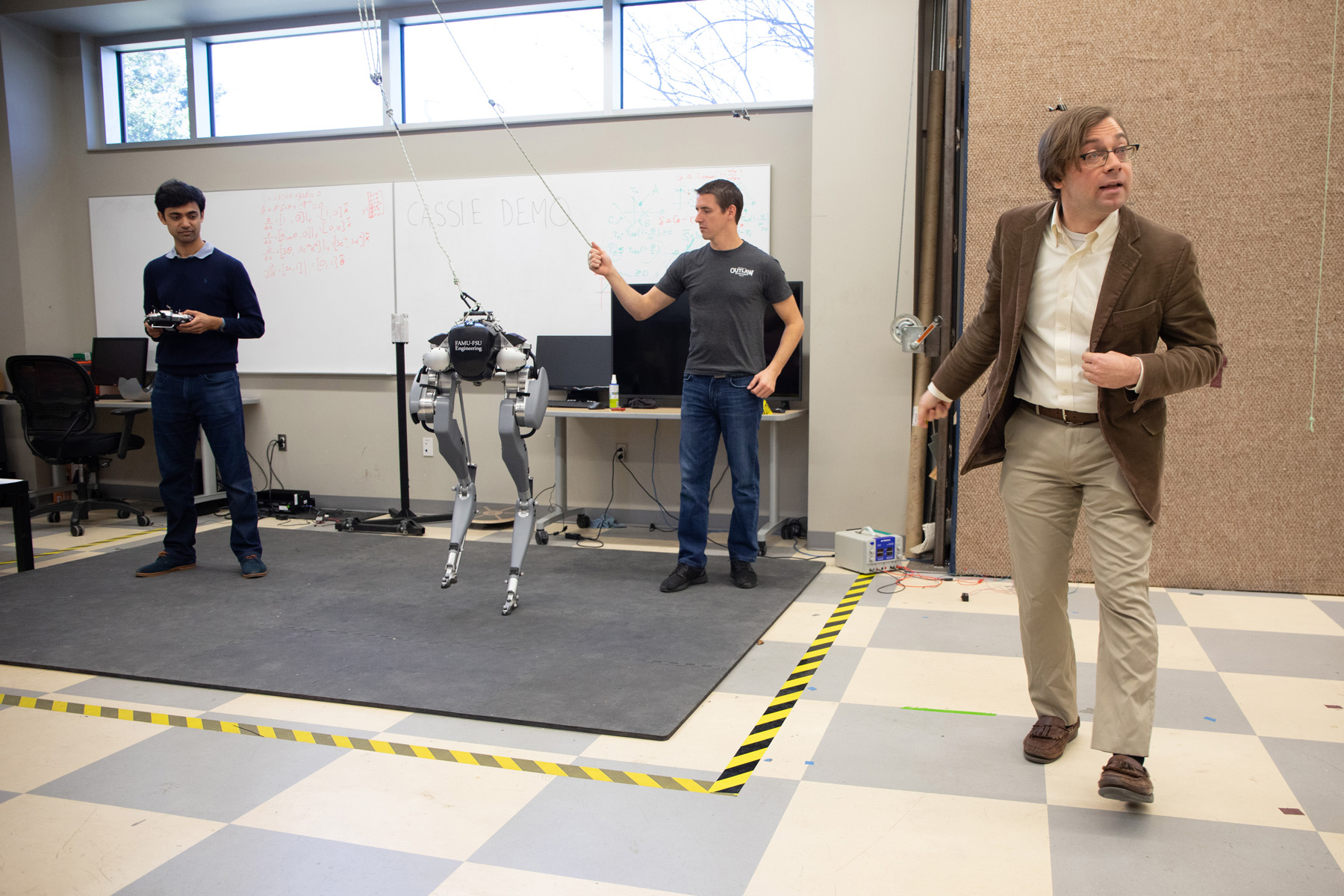 Three men demonstrating a robot