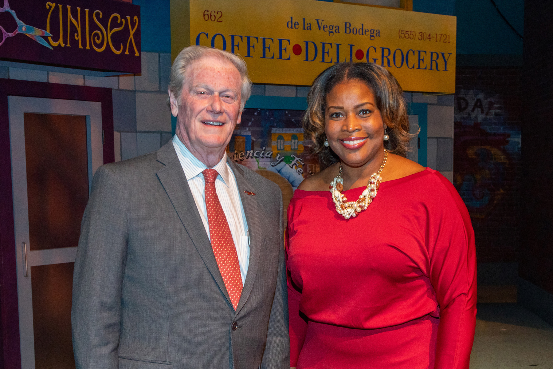 A man in a gray suit and a woman in a red dress smiling at the camera