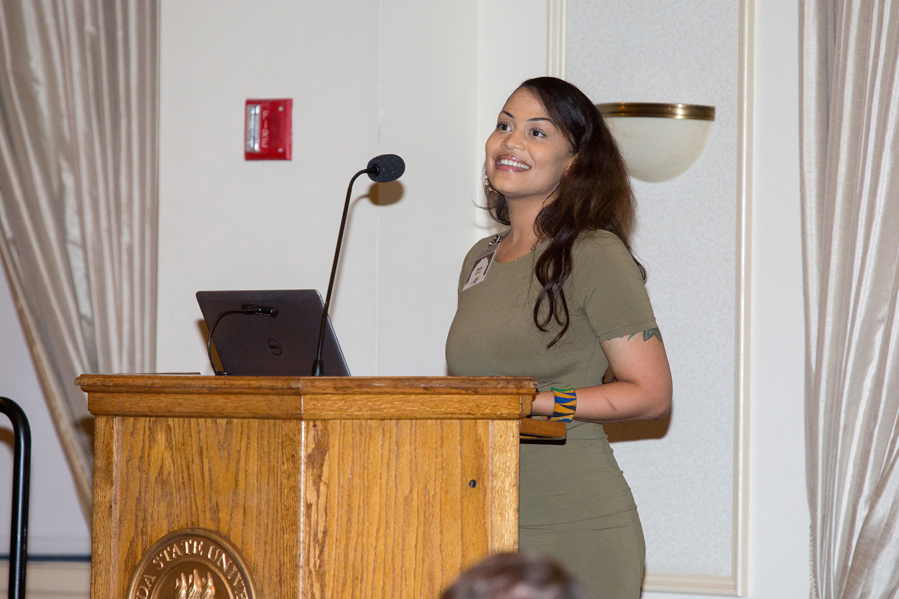 A photo of a young woman standing at a podium, smiling