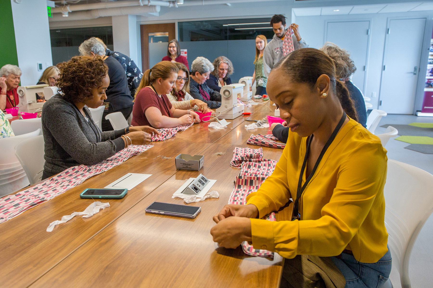 A photo of a group of people at a table crafting with colorful fabric