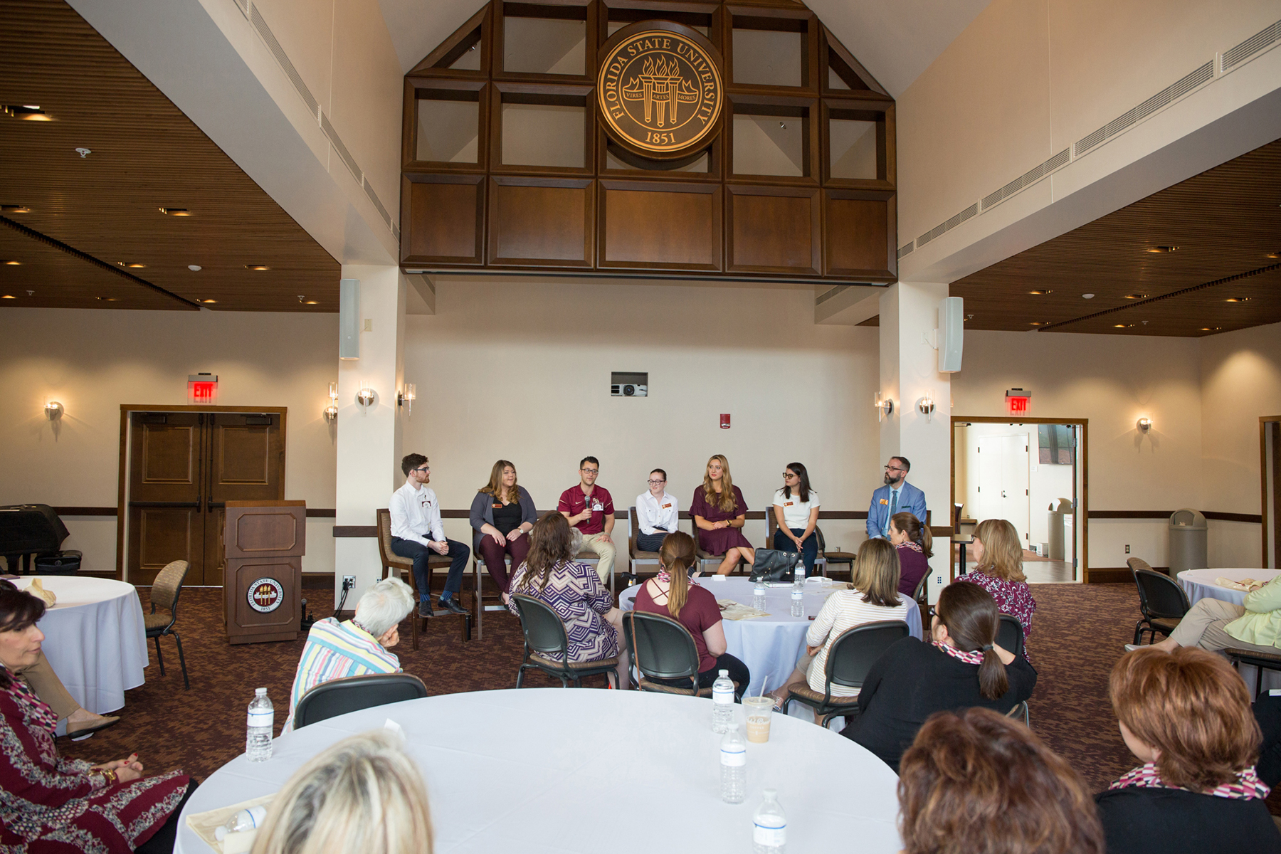 A photo of a panel of people speaking to an audience in a conference room