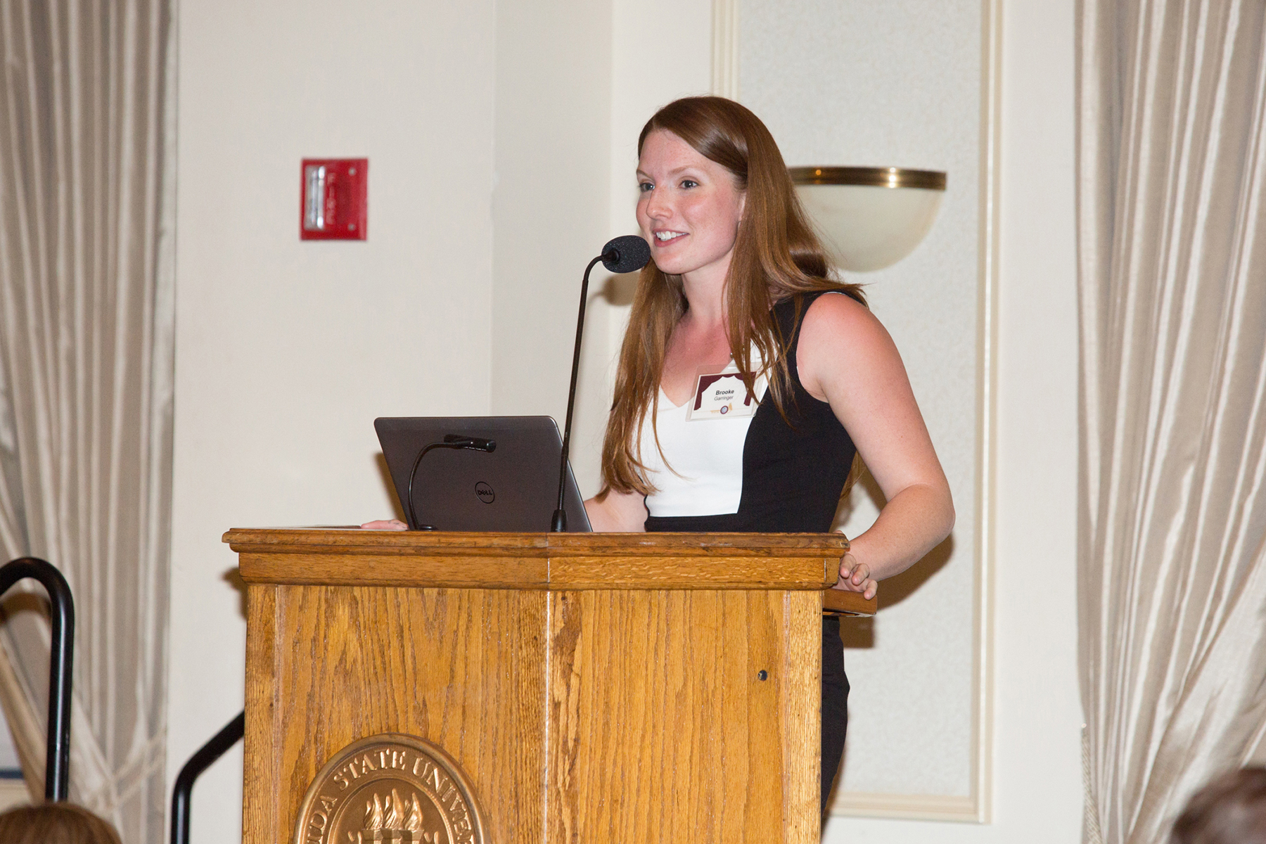 A photo of a woman standing at a podium, speaking