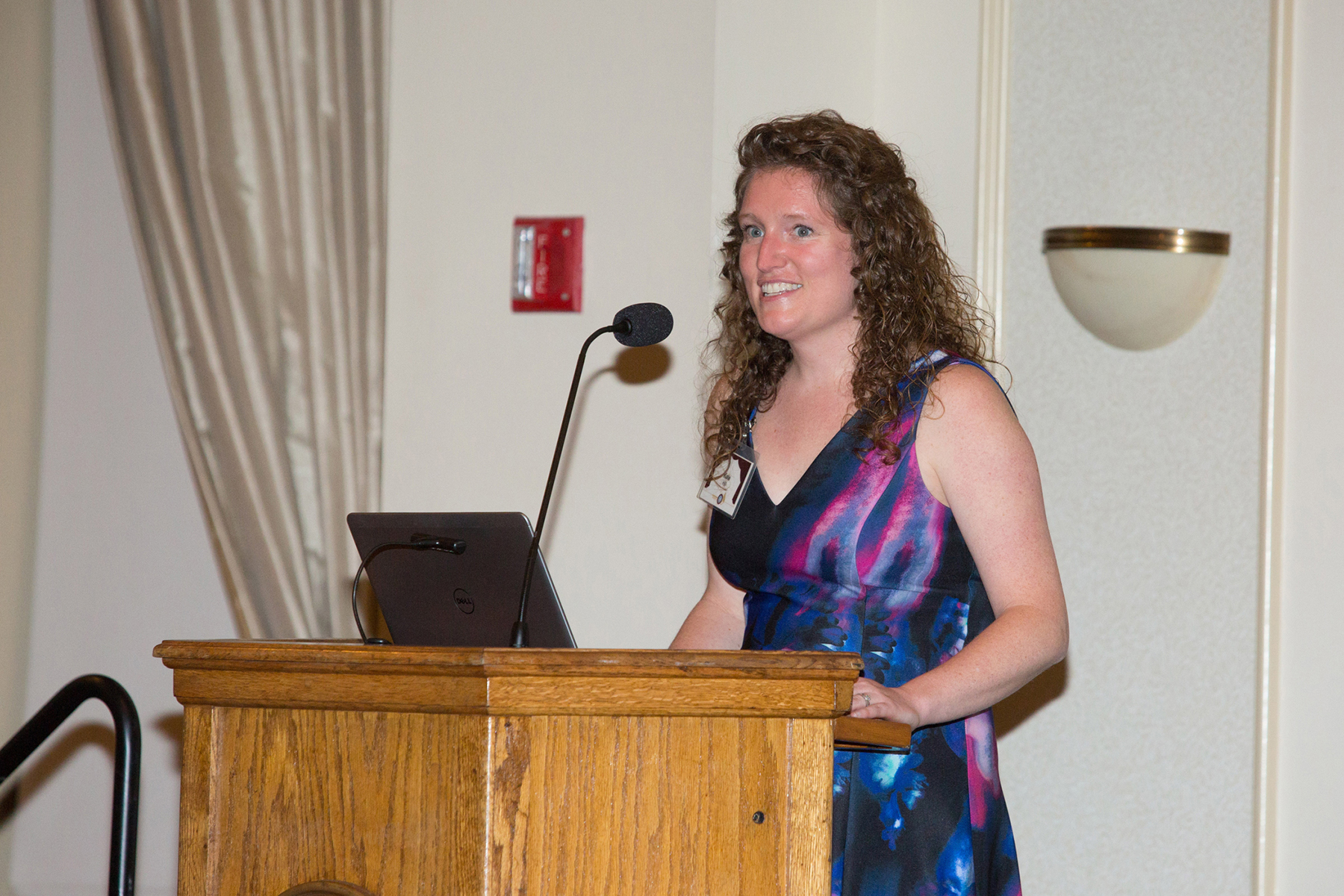 A photo of a woman standing at a podium, smiling