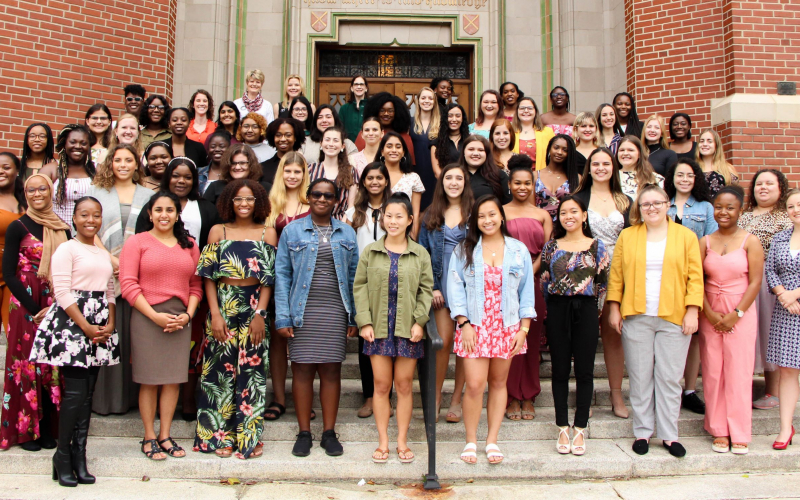 A large group of women standing outside on steps, smiling