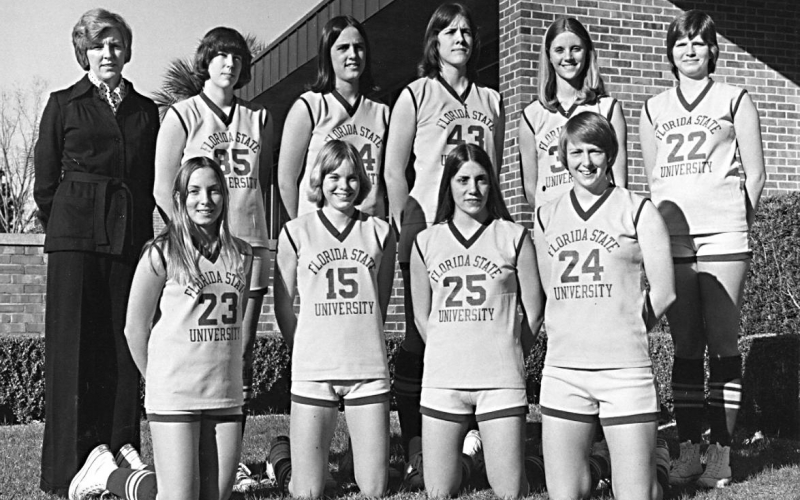 Black and white photo of Dr. Usher standing next to nine women basketball players