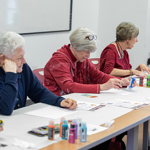 Three women 4 FSU attendees working on a painting project