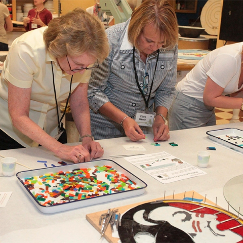 Two women assembling a colorful craft on a table