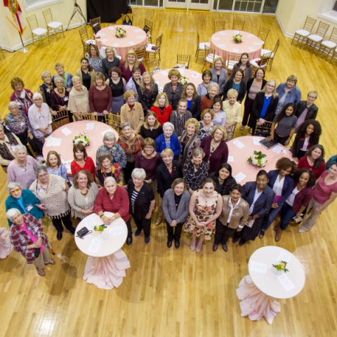 An overhead shot of a large group of woman gathered tightly around several tables